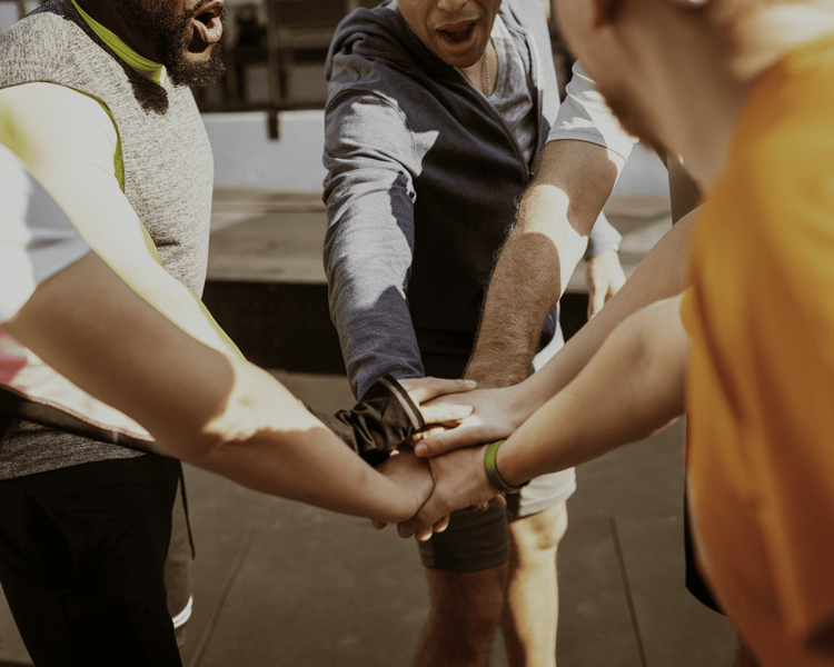a group of people putting their hands together in a huddle