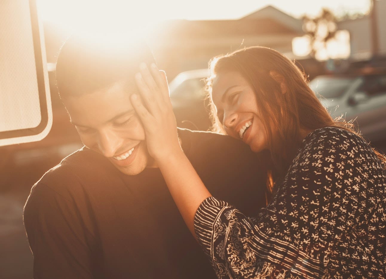 a woman is putting her hand on a man 's ear .