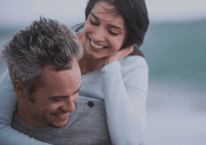 a man is carrying a woman on his back and they are smiling