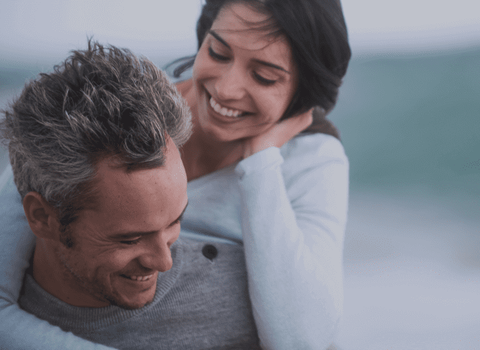 a man is carrying a woman on his back and they are smiling