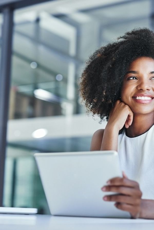 a woman is sitting at a desk using a tablet computer .
