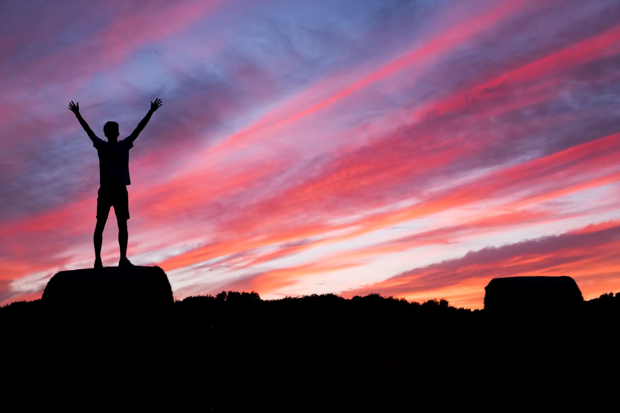 a man stands on top of a rock with his arms in the air