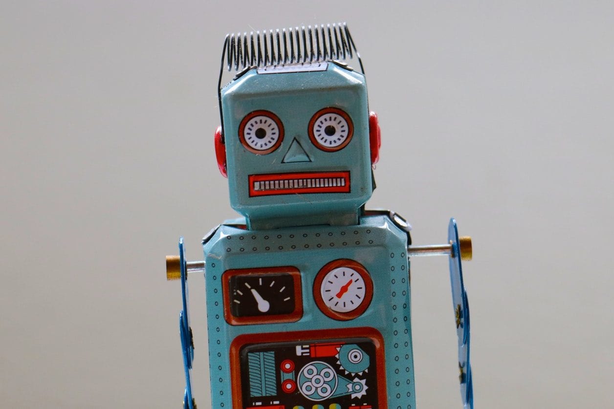 a blue toy robot with a red face is sitting on a table .