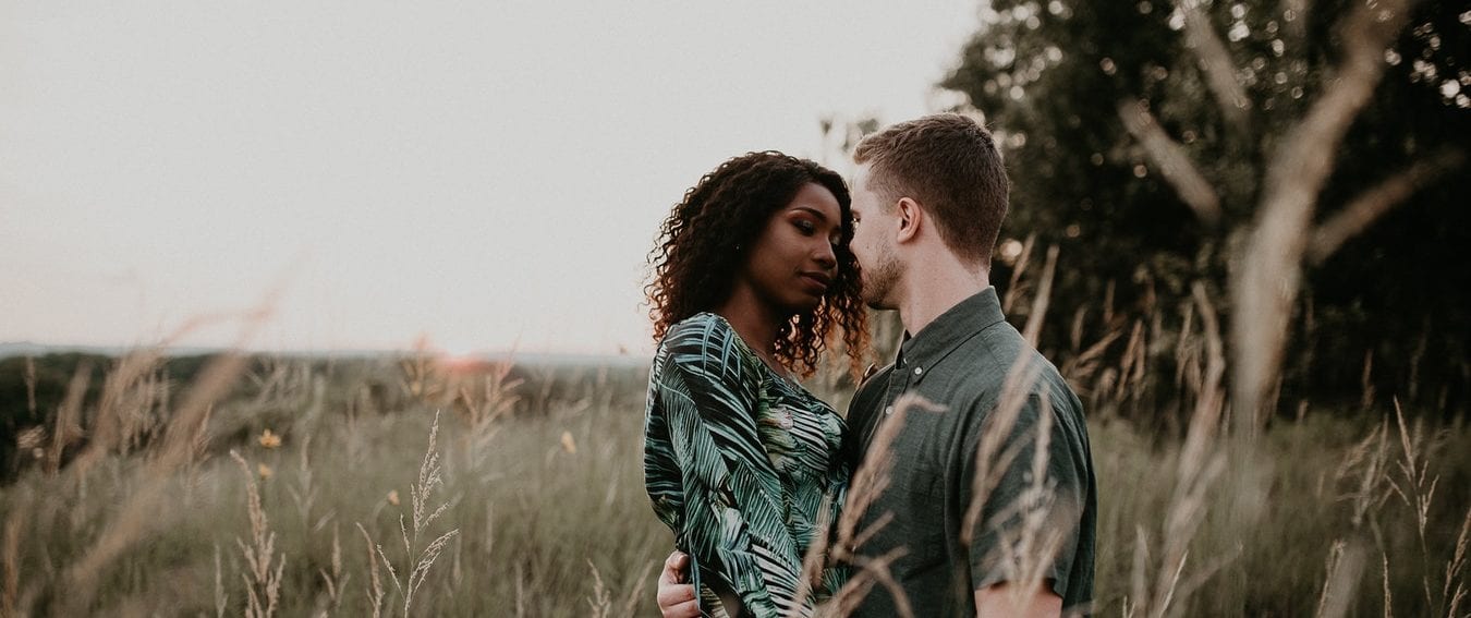 a man and a woman are standing in a field looking at each other .