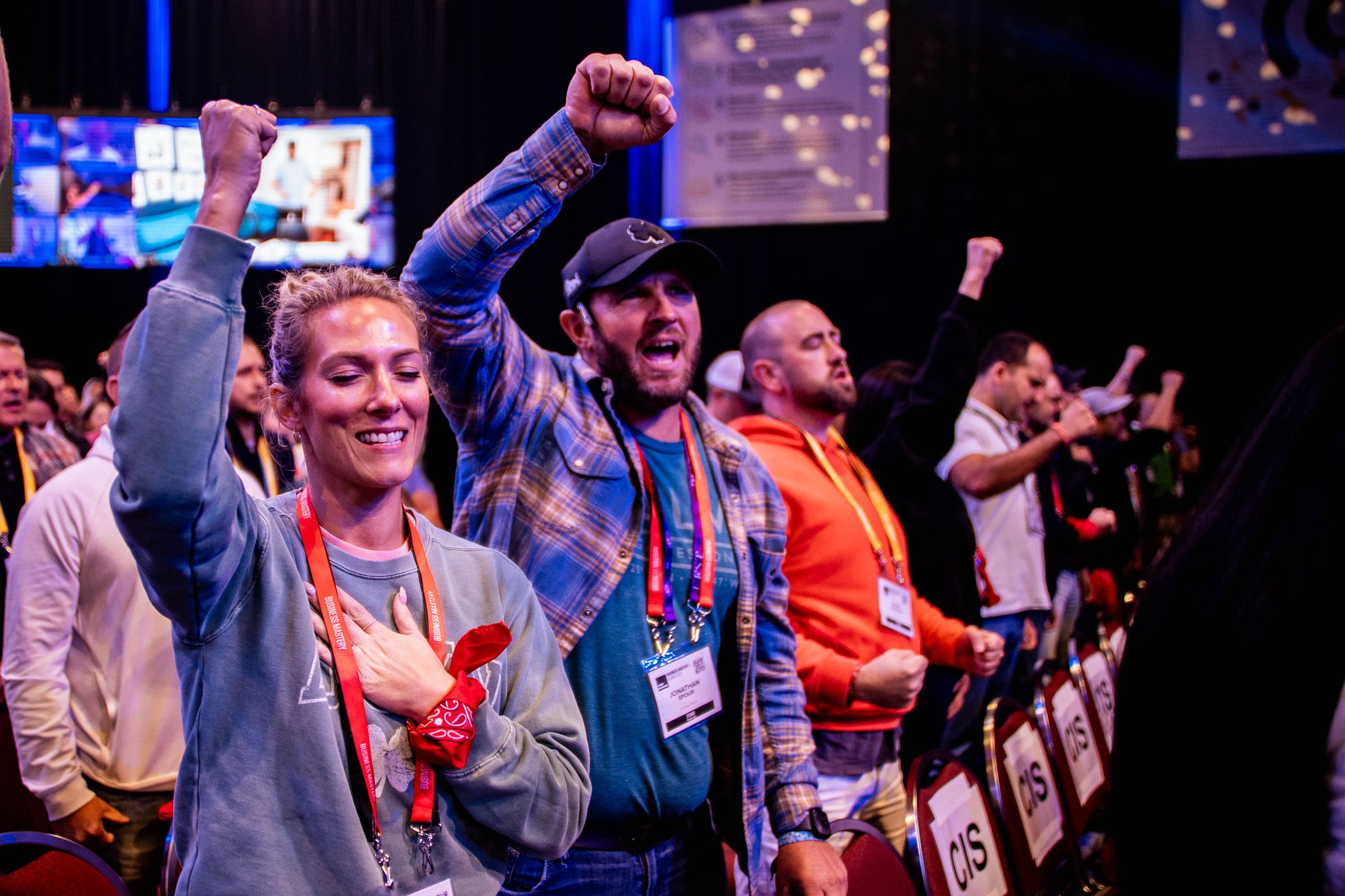 a group of people are standing in a room with their hands in the air .