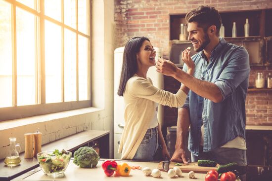 a man is feeding a woman a piece of food in the kitchen .