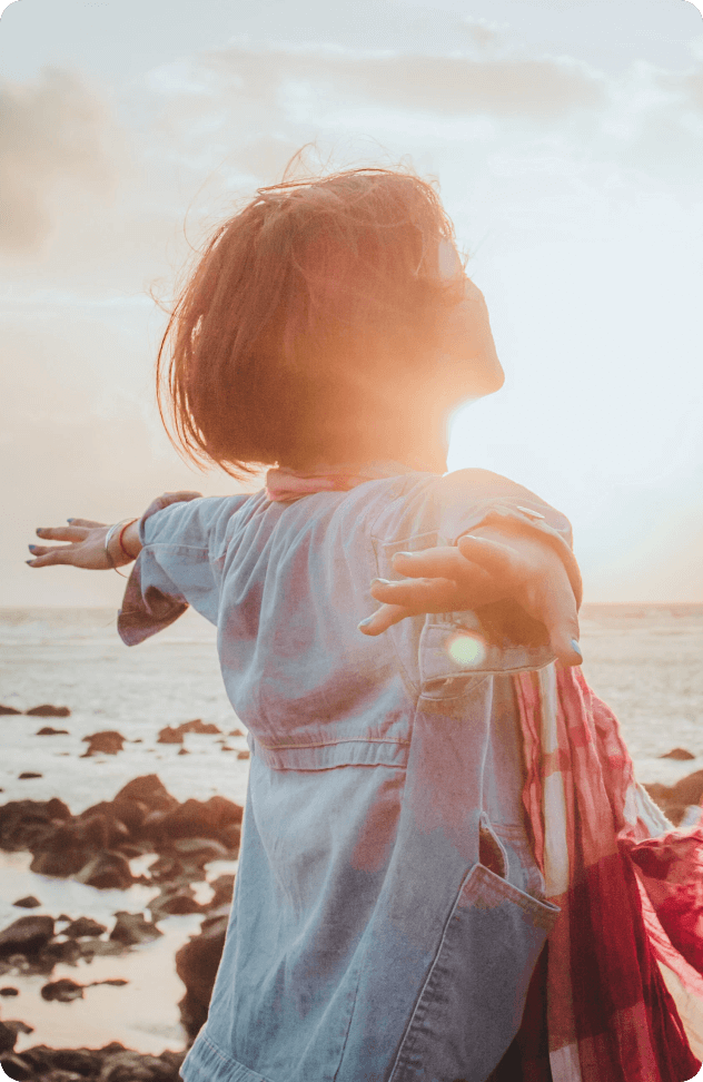 a woman with her arms outstretched in front of the ocean