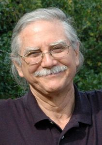a man with glasses and a mustache is smiling for the camera .