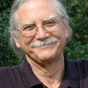 a man with glasses and a mustache is smiling for the camera .