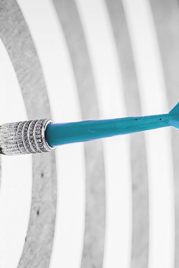 a blue dart is hitting the center of a target .