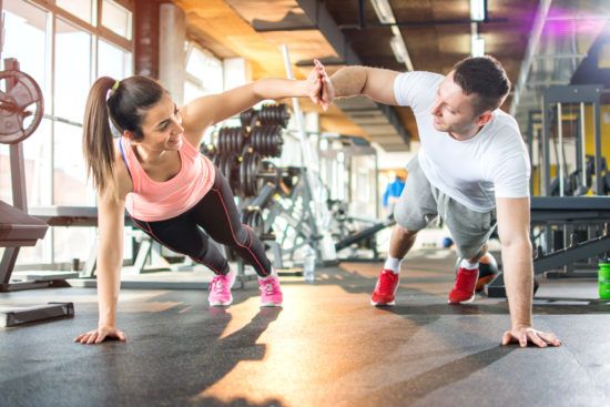 a man and a woman are doing push ups together in a gym .
