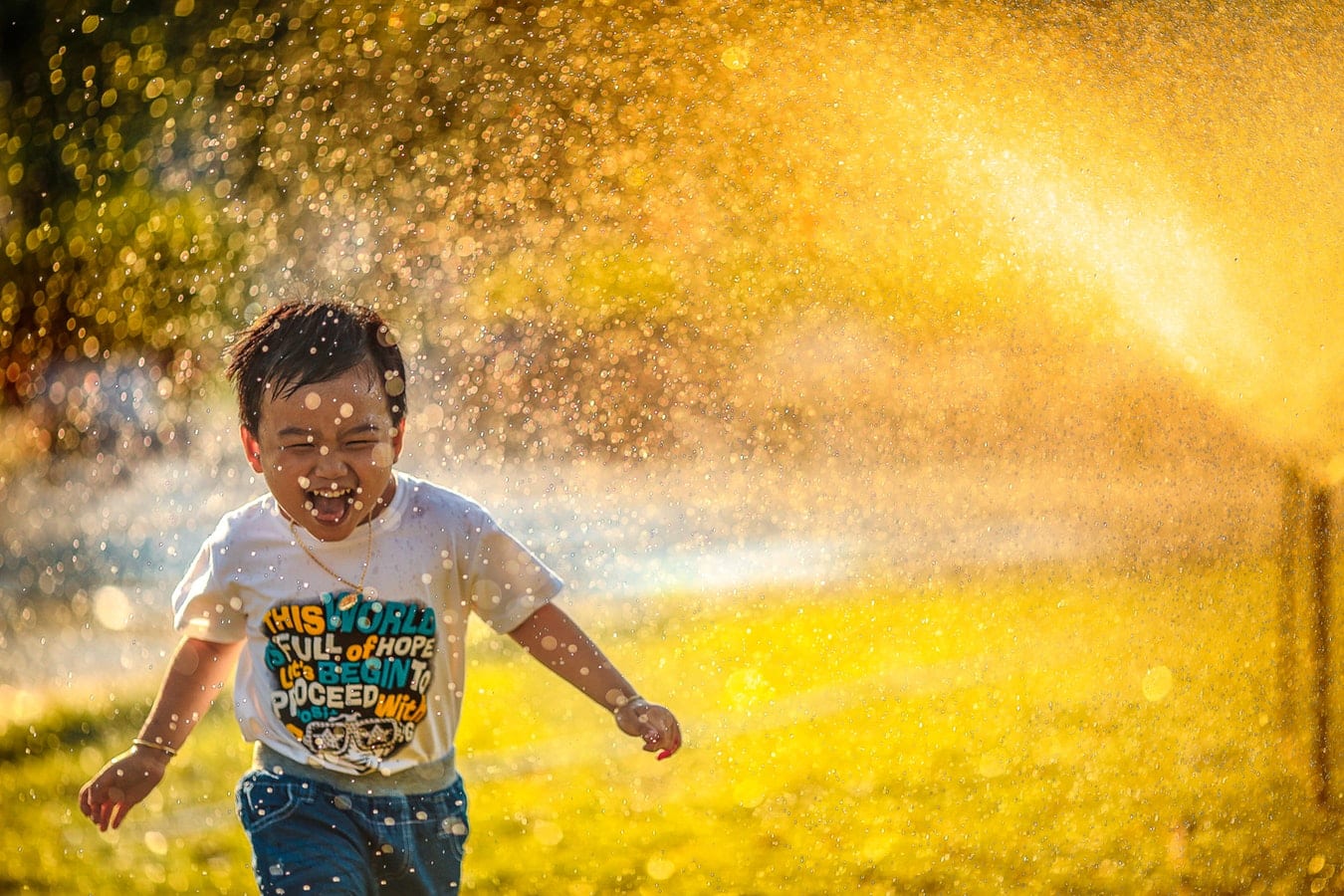 Child running in garden sprinklers