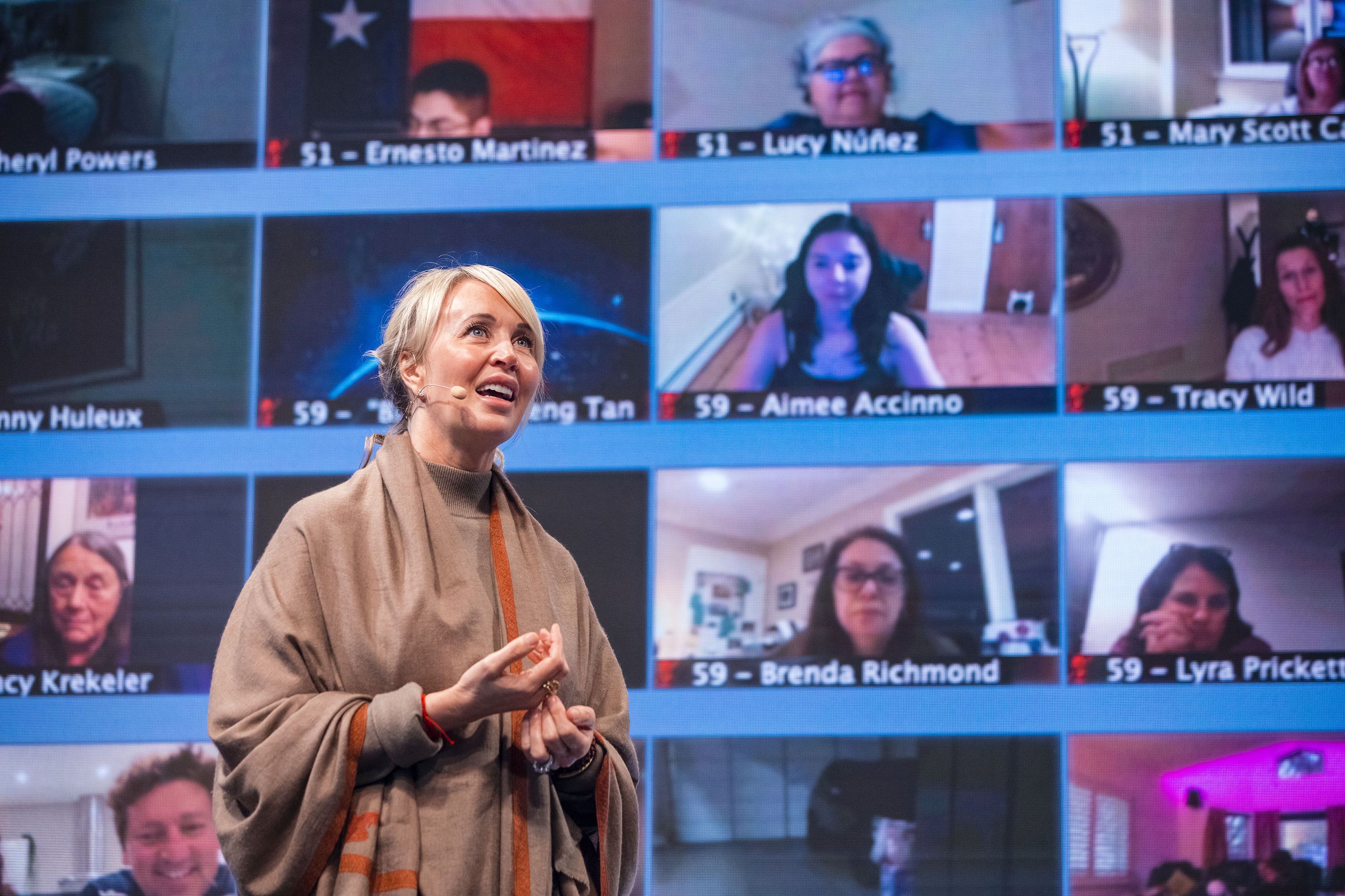 a woman is giving a speech in front of a large screen .