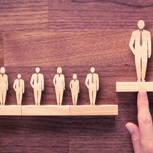 a person is pointing at a wooden block with a man standing on it .