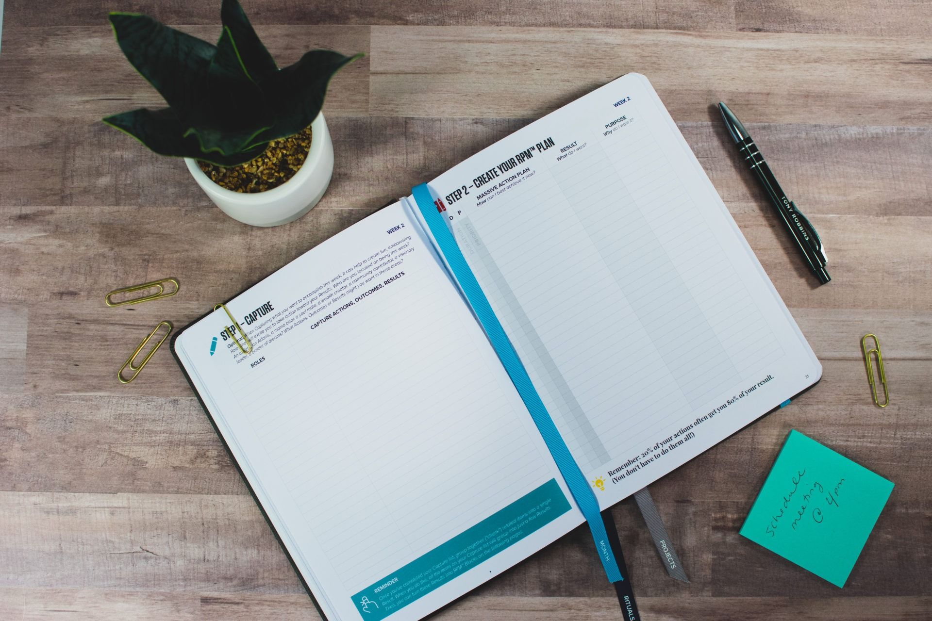 a notebook is open to a page with a pen and sticky notes on a wooden table .