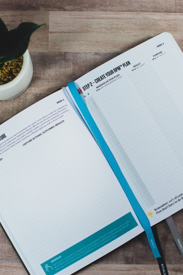 a notebook is open to a page with a pen and sticky notes on a wooden table .