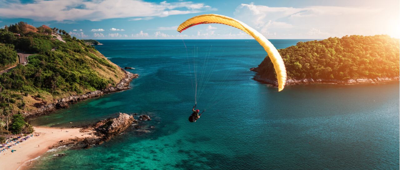a person is parasailing over a body of water .