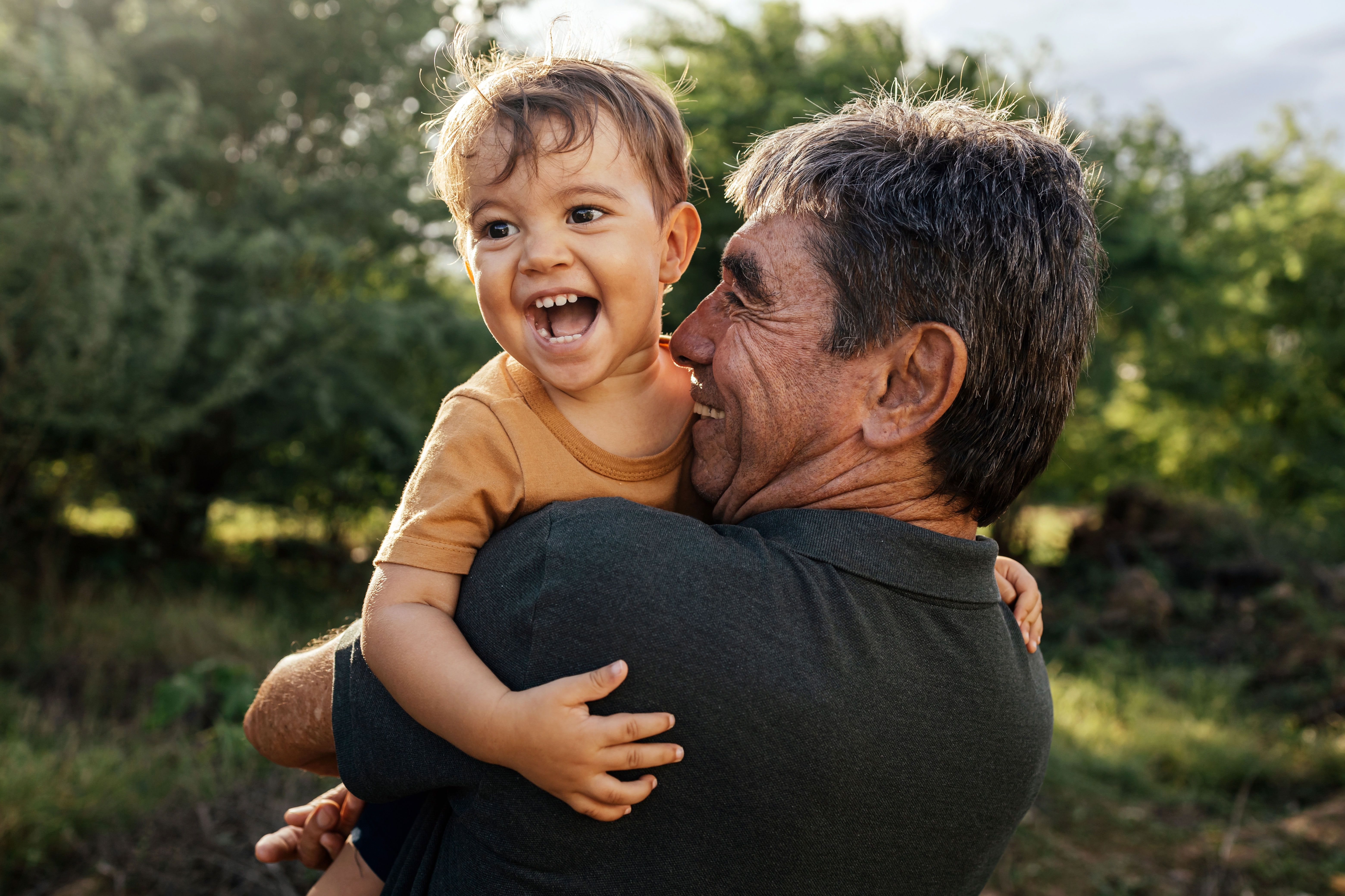 a man is holding a baby in his arms and the baby is smiling .