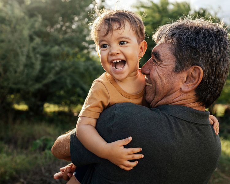 a man is holding a baby in his arms and the baby is smiling .