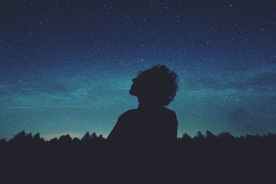 a silhouette of a person looking up at the stars at night .