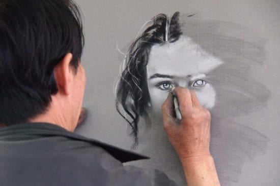 a man is drawing a portrait of a woman 's face with a pencil .
