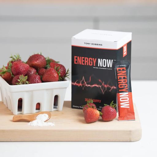 a box of energy now next to a bowl of strawberries on a cutting board .