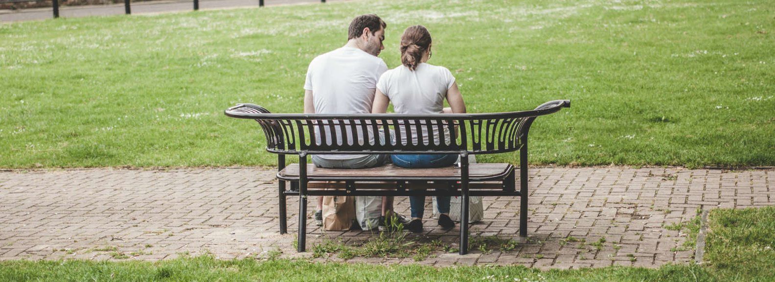 a man and a woman are sitting on a park bench .