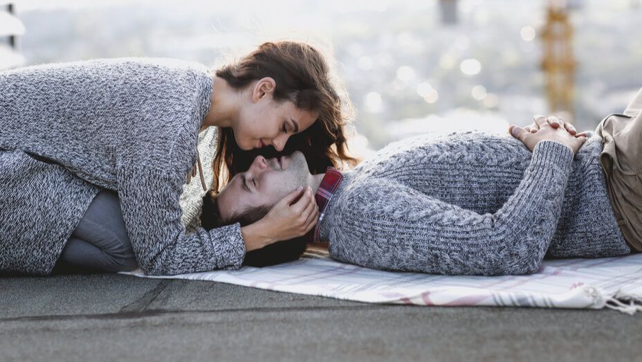 a man and a woman are laying on a blanket on the ground .