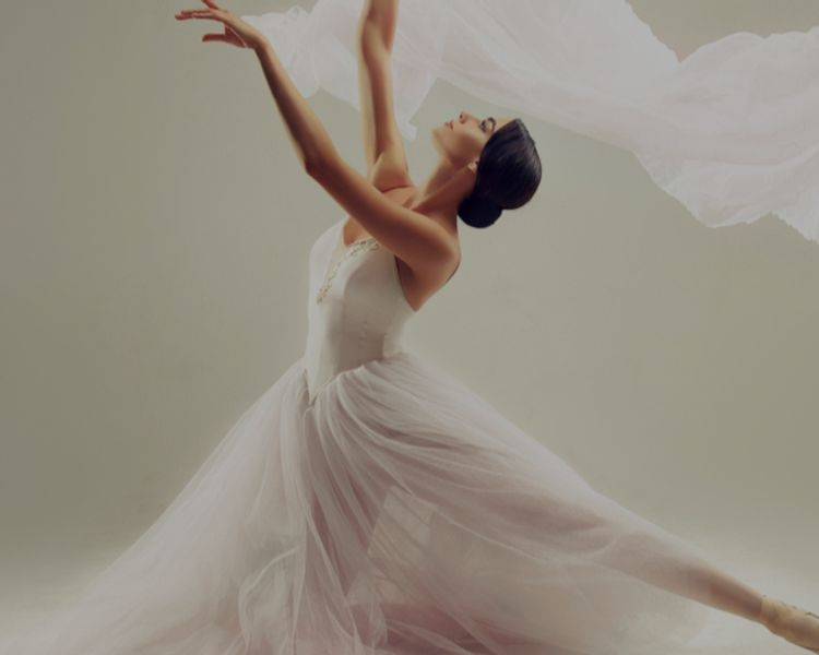 a ballerina in a white dress is dancing with a white cloth flying in the air .