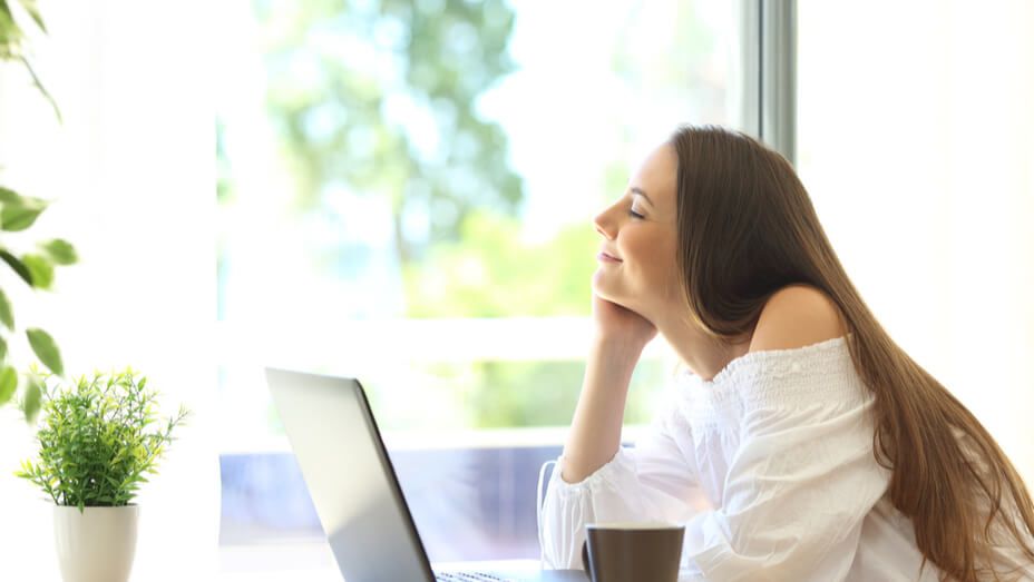 a woman is sitting at a table with a laptop and a cup of coffee .
