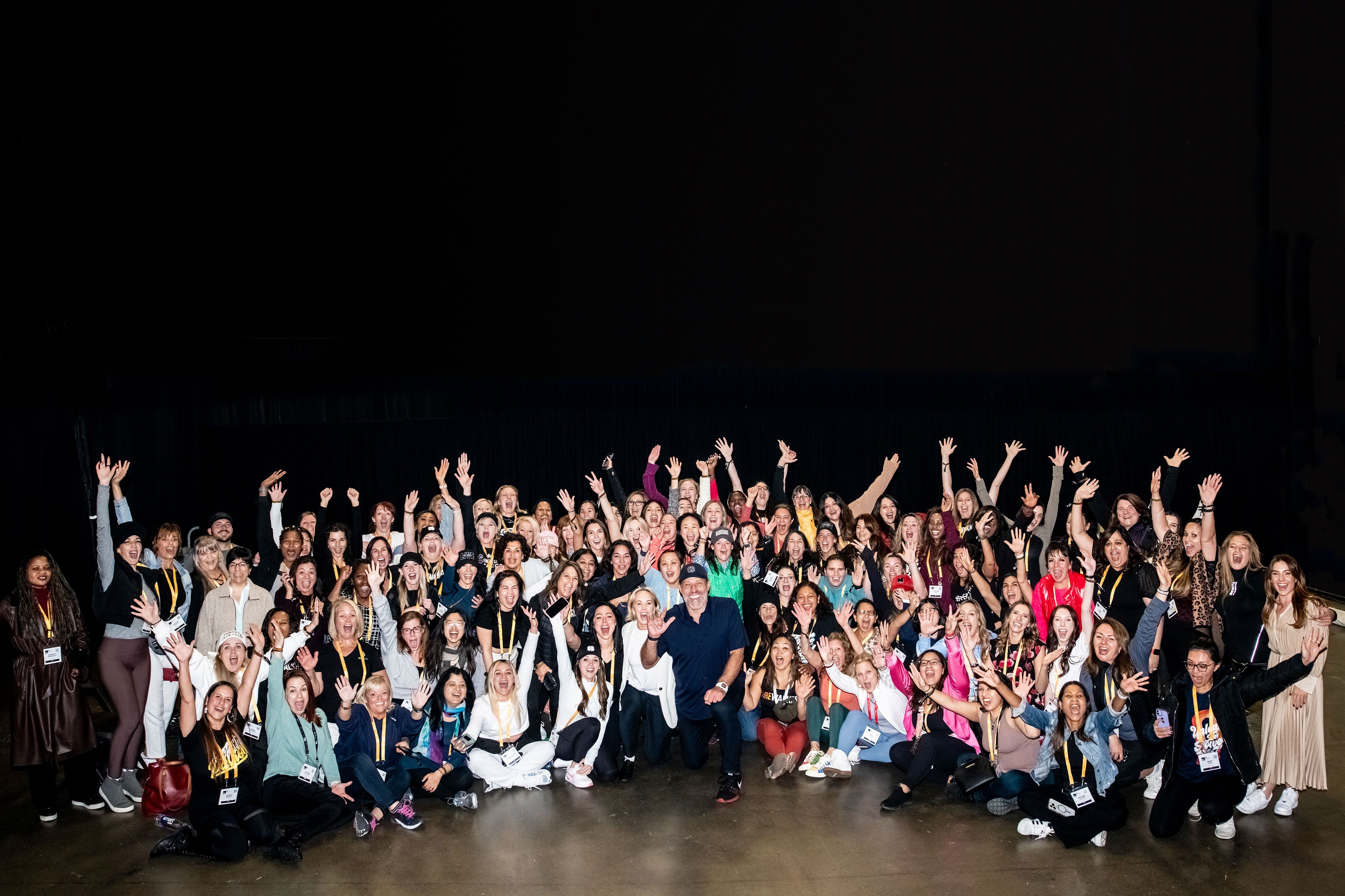 a large group of people are posing for a picture in front of a black background .