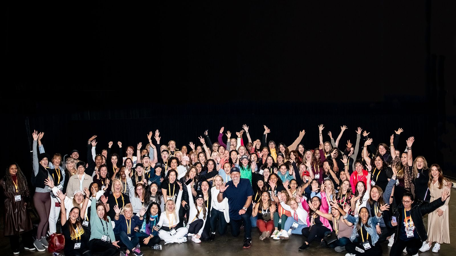 a large group of people are posing for a picture in front of a black background .