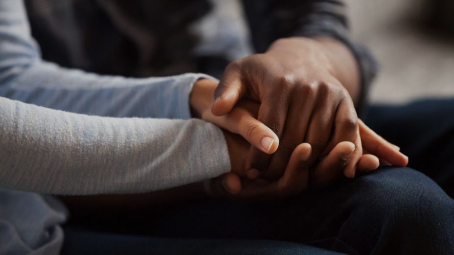 a man and a woman are holding hands while sitting on the floor .
