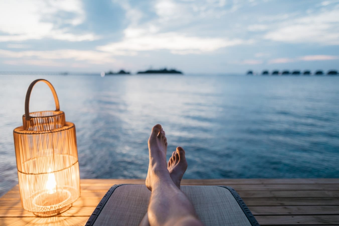 a person is laying on a dock with their feet up in front of the ocean .