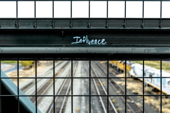 a fence with the word influence written on it and a train track in the background .