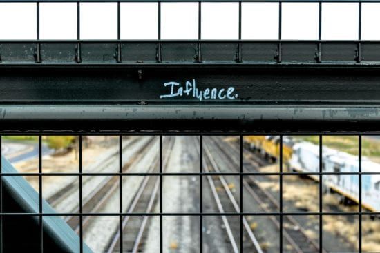 a fence with the word influence written on it and a train track in the background .