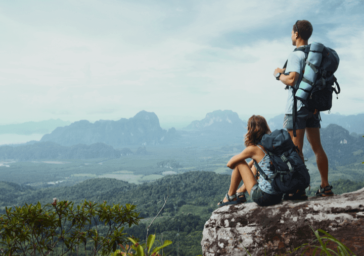 a man and a woman with backpacks looking out over a mountain range