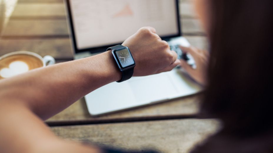 a woman is wearing a smart watch while using a laptop computer .