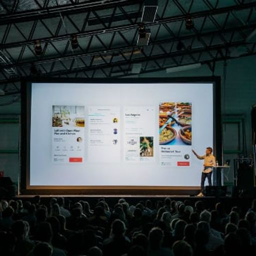 a man is giving a presentation to a large group of people in front of a large screen .