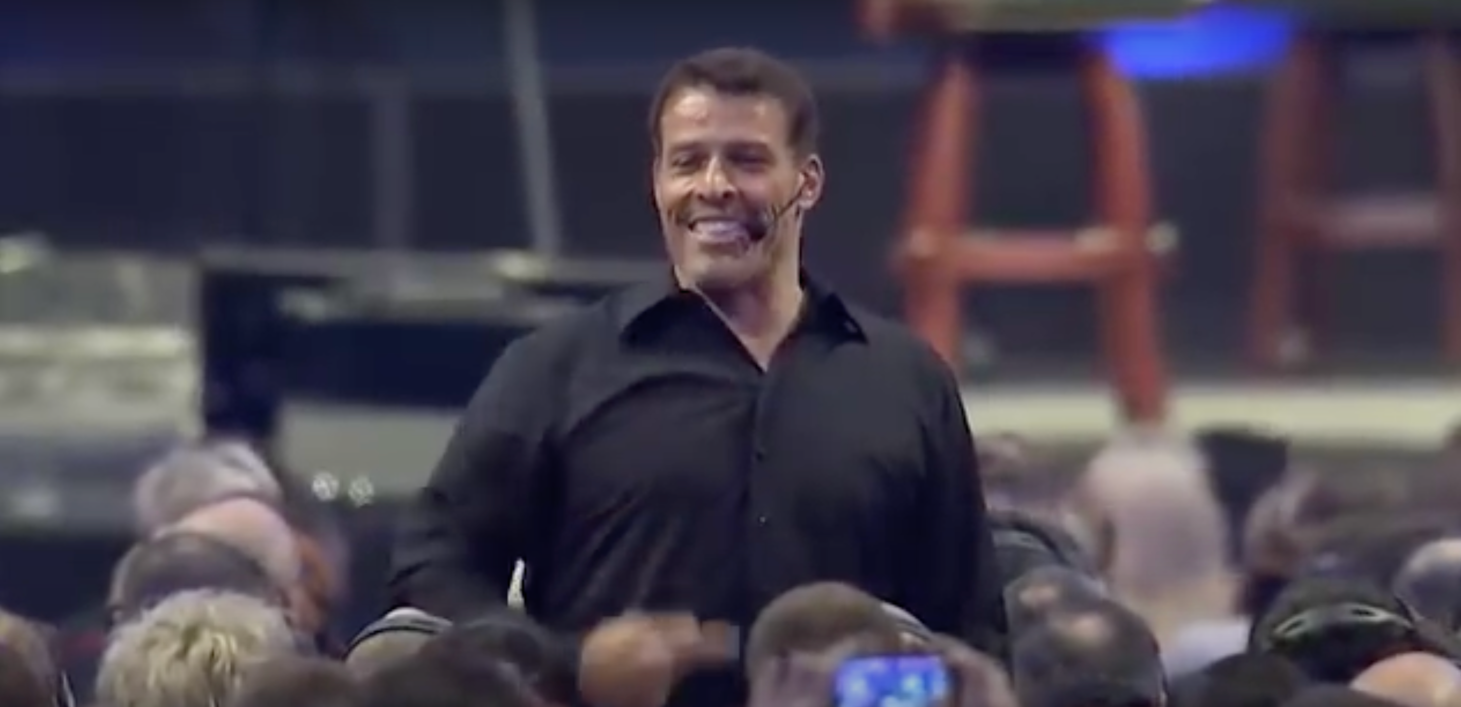 a man in a black shirt is standing in front of a crowd of people .