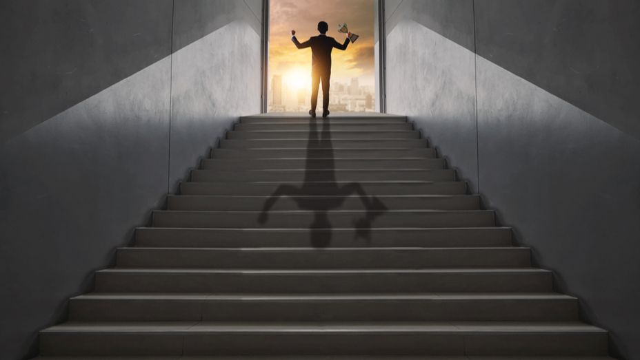 a man is standing on a set of stairs with his shadow on the stairs .