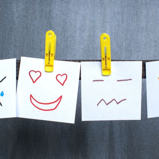 a row of sticky notes with different facial expressions hanging on a clothes line .
