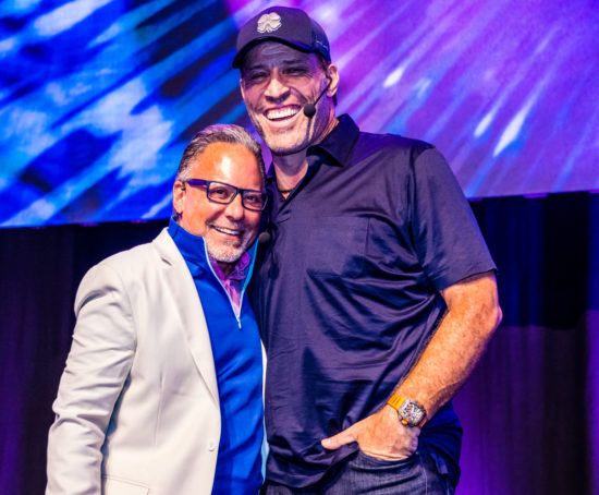 two men are standing next to each other on a stage and smiling .