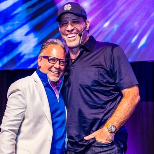 two men are standing next to each other on a stage and smiling .