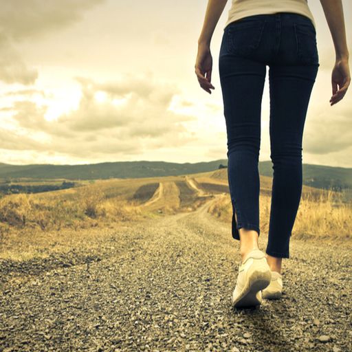 a woman is walking down a dirt road .