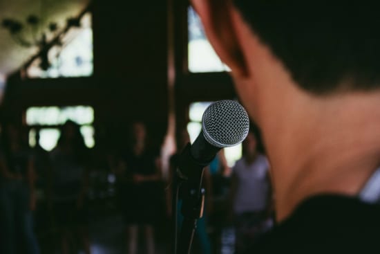 a man is standing in front of a microphone in a dark room .