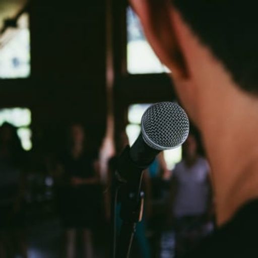 a man is standing in front of a microphone in a dark room .