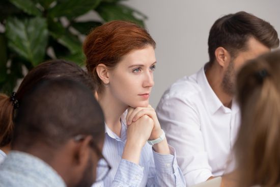 a group of people are sitting at a table having a meeting .