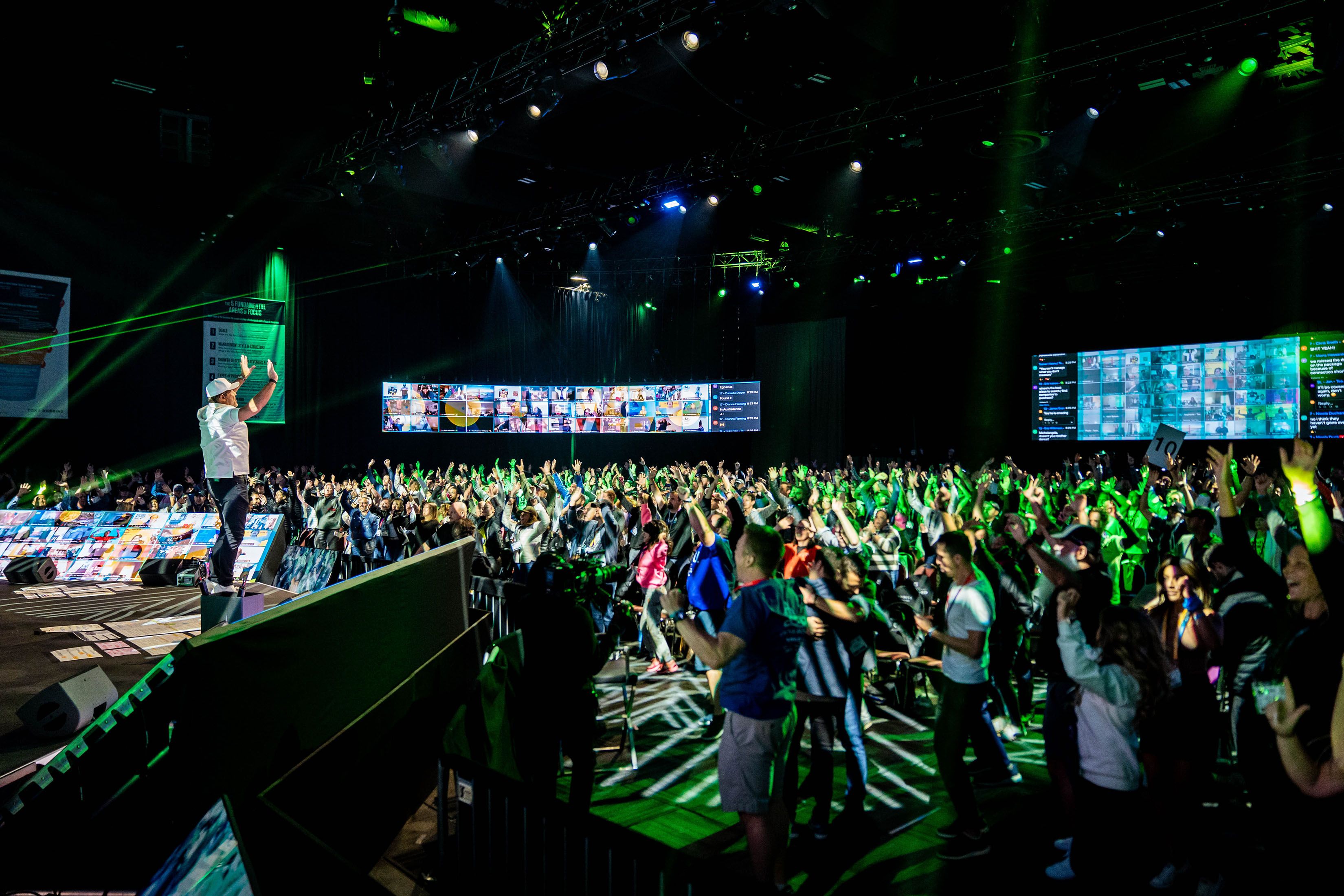 a man is standing on a stage in front of a crowd of people at an event
