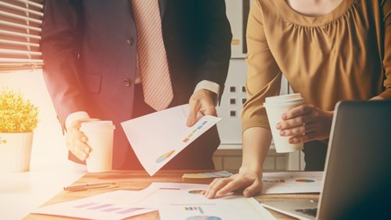 a man and a woman are sitting at a table with papers and a laptop .